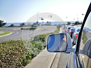 Driving on California roads near the coast with rear view mirror from car in frame.
