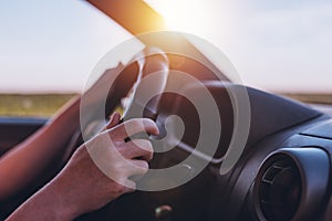 Driving car through countryside, female hands on steering wheel