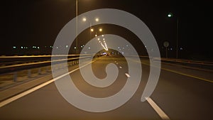 Driving a car on a night highway, point of view. Street lights illuminate track