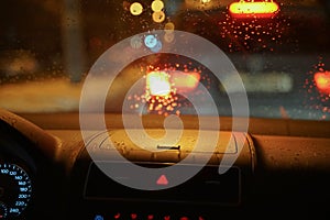 Driving car in the rain at night. Rainy weather view through the windshield with raindrops. Dash cap close up