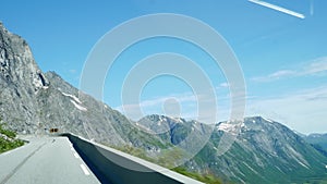 Driving in a car up switchbacks on a steep mountain road in Norway with point of view through front windshield.