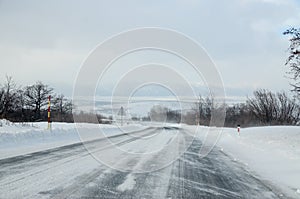 Driving a car on the white and snowy road with a strong wind. Winter weather scene and blizzard. Winter storm. Cars on dangerous