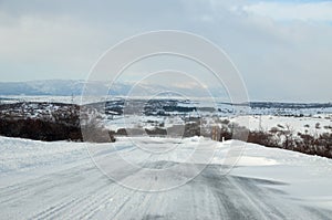 Driving a car on the white and snowy road with a strong wind. Winter weather scene and blizzard. Winter storm. Cars on dangerous