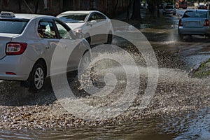 Driving cars on a flooded road during floods caused by rain storms. Cars float on water, flooding streets. Splash on the machine.