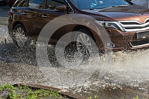 Driving cars on a flooded road during floods caused by rain storms. Cars float on water, flooding streets. Splash on the machine.