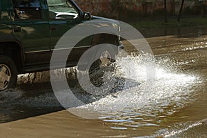 Driving cars on a flooded road during floods caused by rain storms. Cars float on water, flooding streets. Splash on the machine.