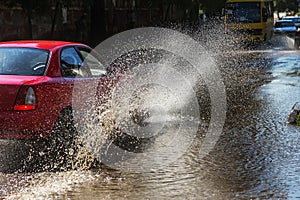 Driving cars on a flooded road during floods caused by rain storms. Cars float on water, flooding streets. Splash on the machine.