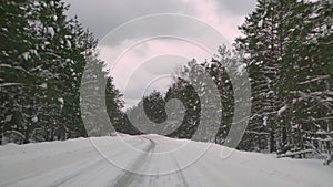 Driving with caution on a slippery road covered with snow in the forest. Car driving on empty path in winter