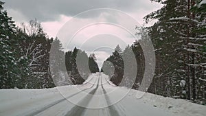 Driving with caution on a slippery road covered with snow in the forest. Car driving on empty path in winter