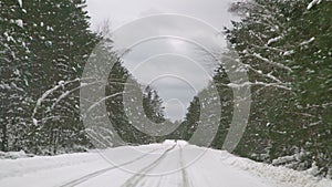 Driving with caution on a slippery road covered with snow in the forest. Car driving on empty path in winter