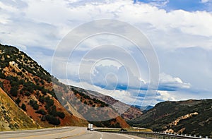 Driving curved road through the mountians with beautiful blue cloudy sky and tunnel in the distance photo