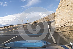 Driving on a curved uphill road beside a rocky mountain in Hurricane, Utah