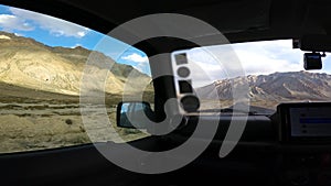 Driving on Dusty Trails with a Car Window View of Mountains and Clouds