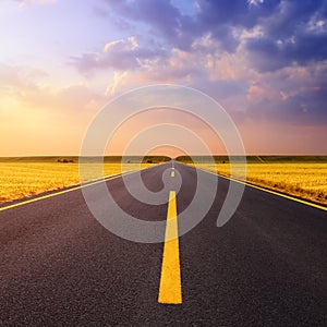 Driving on an empty asphalt road at sunset