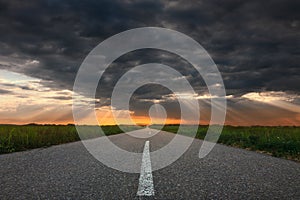 Driving on an empty asphalt road towards the sunbeams