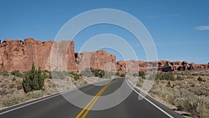 Driving on empty road through amazing arches national park in Utah on sunny day