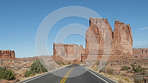 Driving On Empty Road In Arches National Park With Red Rocks Buttes In Desert