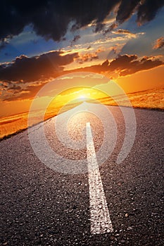 Driving on an empty road towards the setting sun