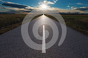 Driving on an empty road towards the setting sun