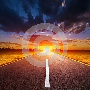 Driving on an empty road towards the setting sun