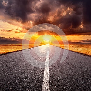 Driving on an empty road towards the setting sun