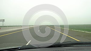 Driving in the gloomy weather. View from inside car with rain drops on car windshield.