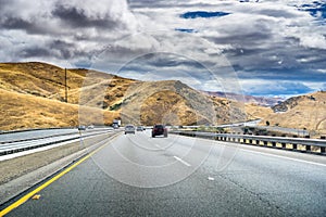 Driving through the golden hills of California in the San Luis Reservoir State Recreation area on a cloudy day