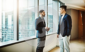 Driving growth with expert discussions. two young businessmen using a digital tablet together in a modern office.