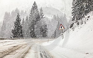 Driving through heavy snowstorm / blizzard on forest road, view from car behind. Snow on ground makes everything slippery -