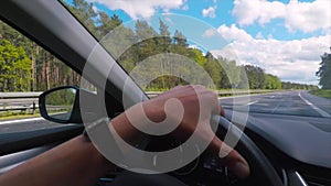 Driving on highway hand holds the steering wheel, vehicle control.
