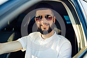 Driving his car, young man smiling while driving a car, Man in the driver`s seat of a car