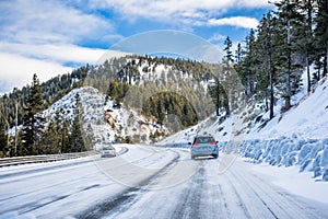 Driving on an ice and snow covered road through the Sierra mountains on a sunny day, Nevada
