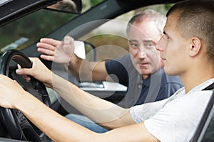 Driving instructor gesturing to young learner driver