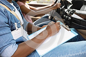Driving instructor taking notes during exam, driving school concept