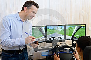 driving instructor watching learner driver use driving simulator