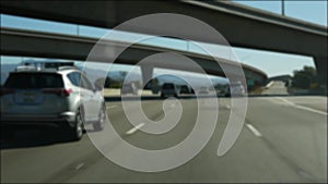 Driving on intercity freeway in Los Angeles, California USA. Defocused view from car thru glass windshield on busy