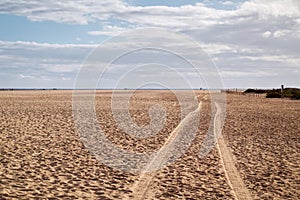 Driving Lanes in the sand on the wide beach of Jandia, under cloudy skies