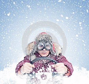 Driving man in red winter clothes and stylish goggles holds a steering wheel in his hands, around the snow. Front view