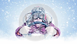 Driving man in red winter clothes and stylish goggles holds a steering wheel in his hands, around the snow. Front view