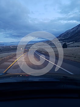 Driving on a o ramp highway road near mountains and stormy clouds