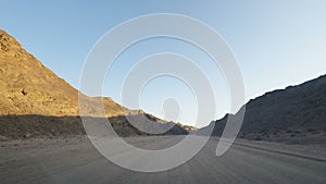 Driving off road on gravel in the Namib Desert, travel destination in Namibia, Africa. View from car mounted camera