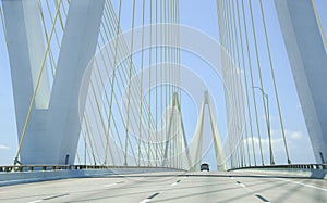 Driving over large cable suspension bridge, with a clear view of the cables and supports and M shaped structure.