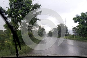 Driving in rain view from inside car with rain drops on car windshield in thailand.