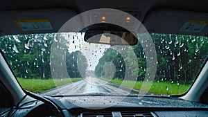Driving on rainy road with rain drops on windshield