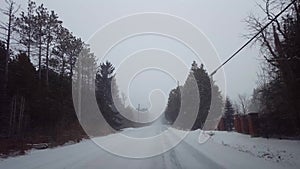 Driving Rural Evergreen Forest Road During Winter Snow Storm in Day.  Driver Point of View POV Snowing Blizzard Snowfall