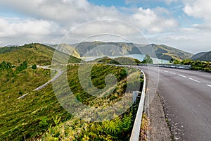 Driving scenic winding road with mountain landscape and Lagoa do Fogo in the background.