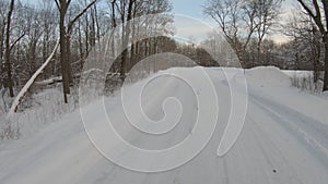 Driving on a snow covered road through forest in winter