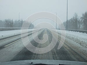 Driving in a storm. Poor visibility through the driver\'s glass onto the road covered with snow and ice. Extreme weather in