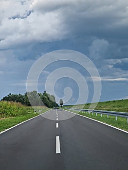Driving on a streight road, cloudy sky and green surroundings