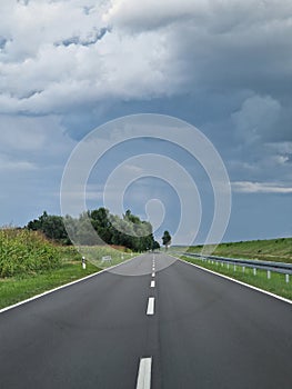 Driving on a streight road, cloudy sky and green surroundings